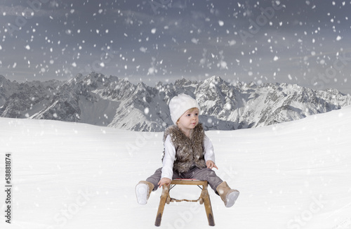 Little toddler outdoors in the snow in the alps