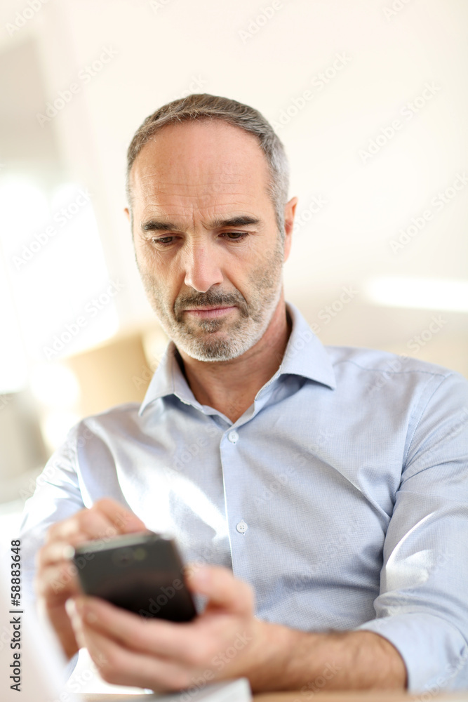 Senior businessman in office using smartphone Senior businessman in office using smartphone