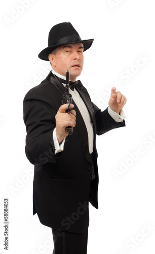 The elegant man in a tuxedo with a hat and a revolver 