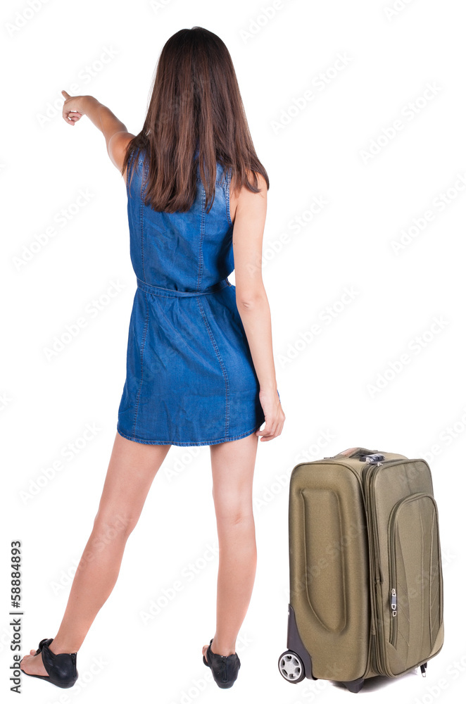 Back view of young brunette woman traveling with suitcas and poi Back view of young brunette woman traveling with suitcas and poi