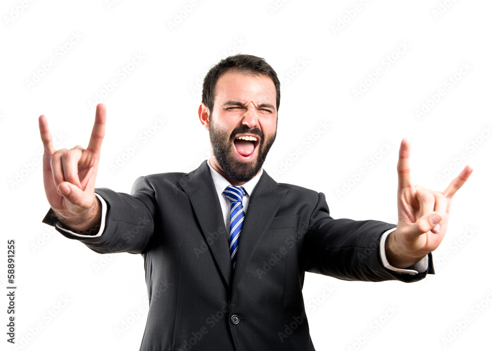 Young businessman doing the horn sign over white background Young businessman doing the horn sign over white background