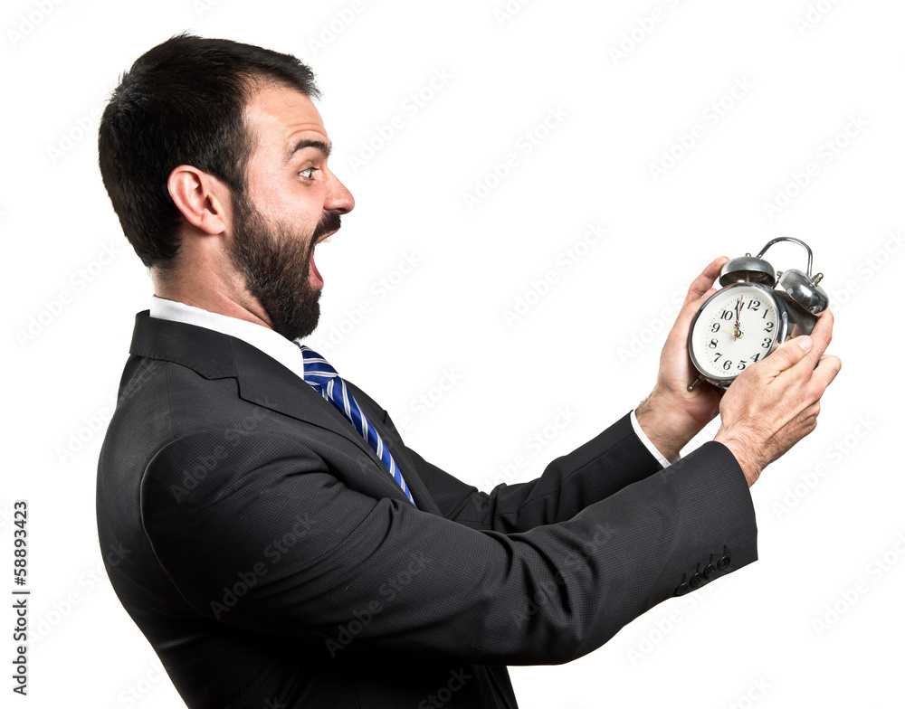 Young businessman holding an antique clock over white background Young businessman holding an antique clock over white background