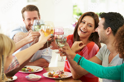 Group Of Friends Making Toast Around Table At Dinner Party