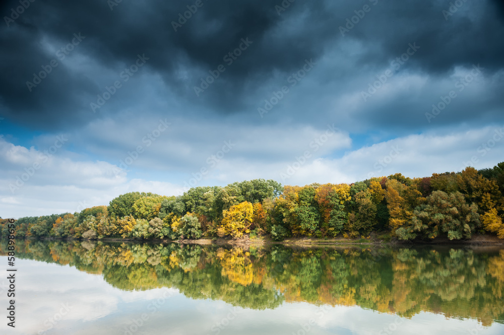 beautiful river and forest with dark sky in autumn