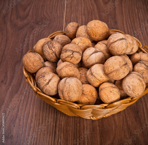 walnuts in a wicker basket on a wooden background