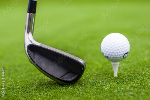 Golf tee ball club driver in green grass course closeup