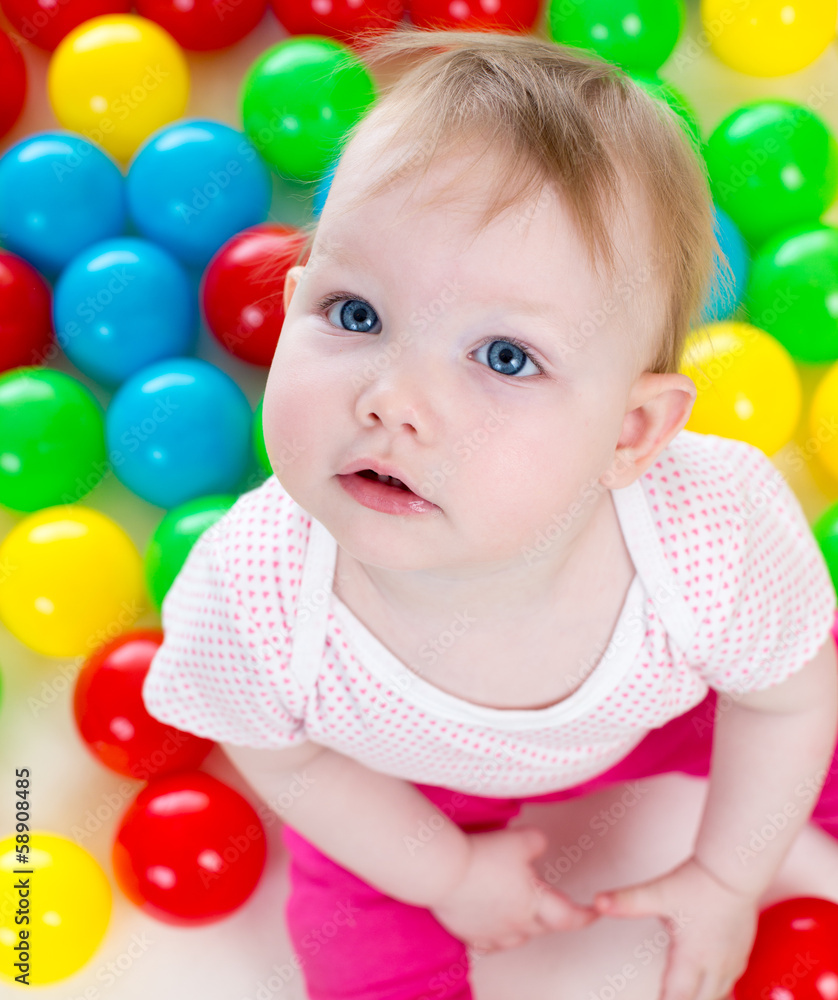 Top view of baby girl playing with colorful balls Top view of baby girl playing with colorful balls