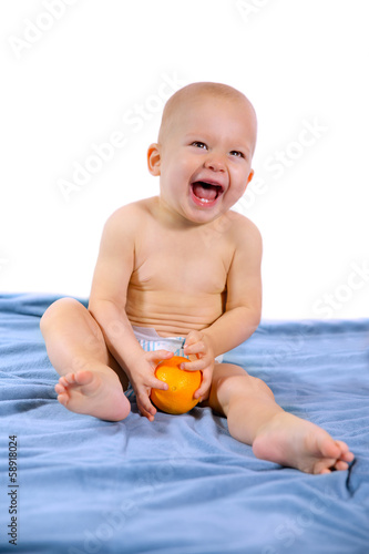 cute one year baby boy holding a orange