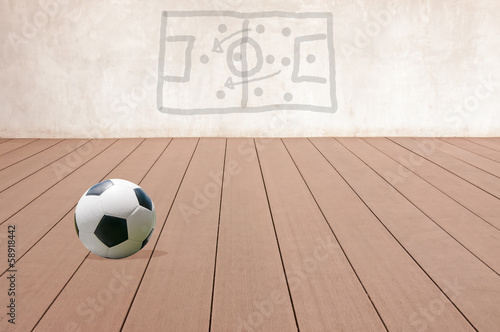 Soccer ball on a wooden floor with a game plan.