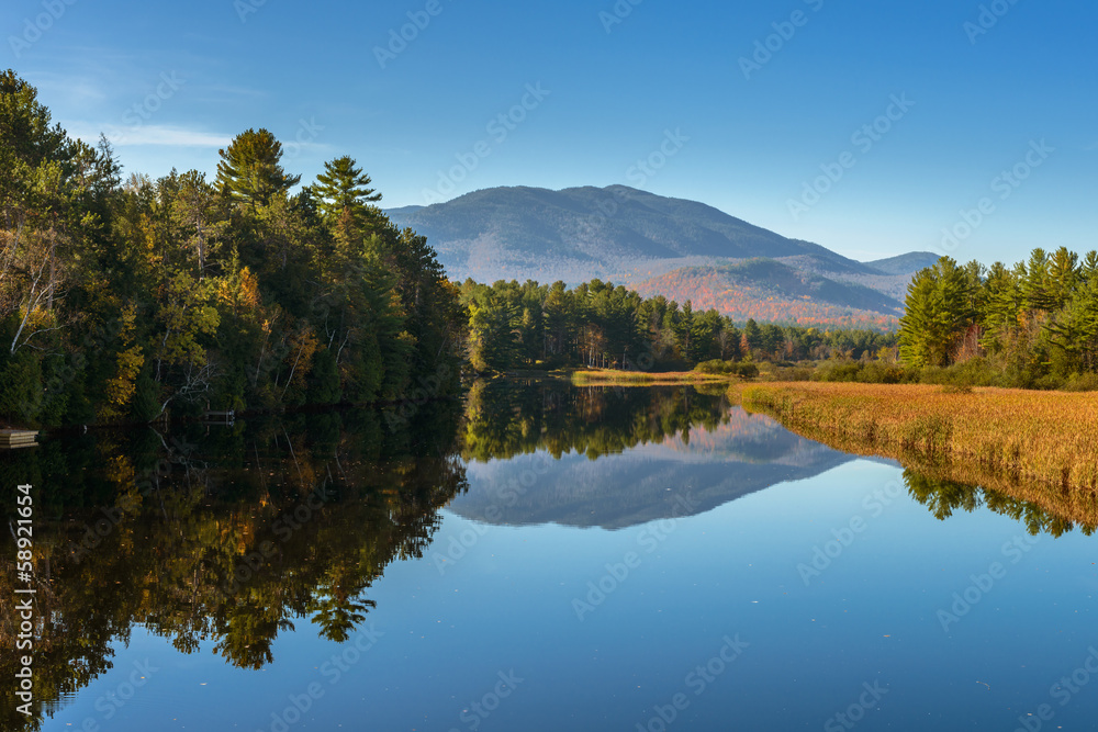 Autumn scenery at sunrise reflected in the water of the river