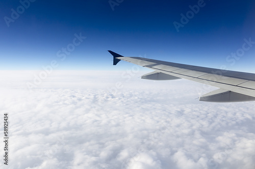 Wing of airplane flying above the clouds in the sky