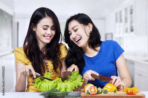 Young women prepare salad together