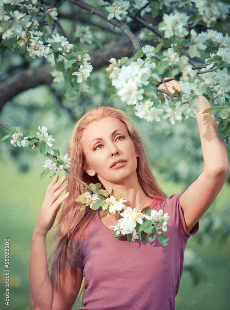 young attractive woman standing near blossoming apple tree young attractive woman standing near blossoming apple tree