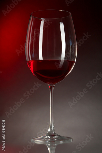 Glass of wine on table on bright red background