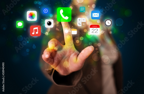 Young businesswoman pressing colorful mobile app icons with boke