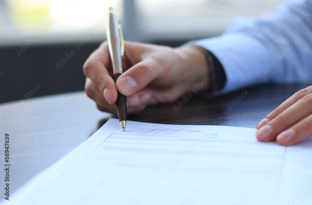 Businesswoman sitting at office desk signing a contract Businesswoman sitting at office desk signing a contract