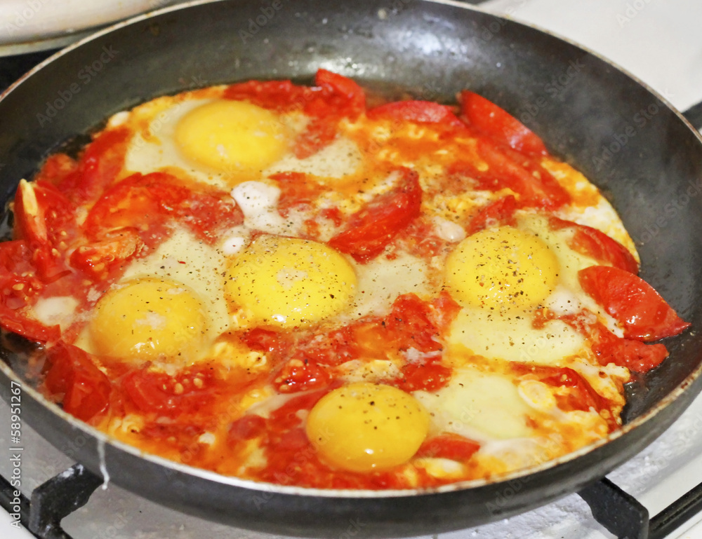 Fried eggs with tomato on the pan Fried eggs with tomato on the pan