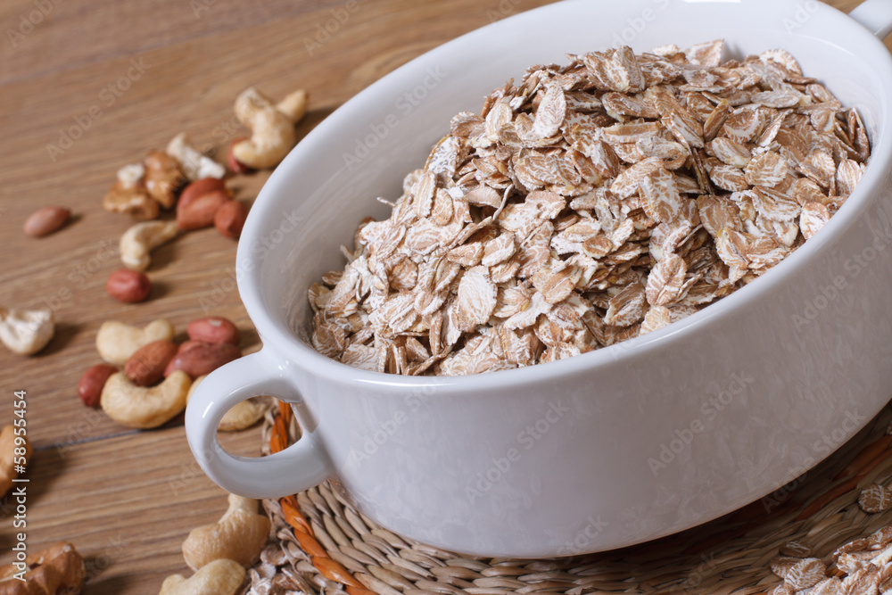 Oat flakes in a bowl and scattered on the table nuts. close-up Oat flakes in a bowl and scattered on the table nuts. close-up