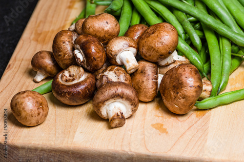 Mushrooms and green beans on a wooden board