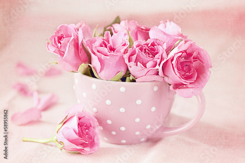 Beautiful fresh roses in a  cup on a pink background