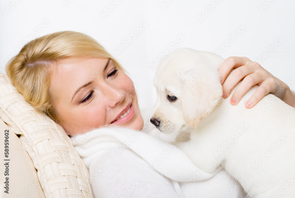 White Labrador puppy lying on the woman on the white sofa White Labrador puppy lying on the woman on the white sofa