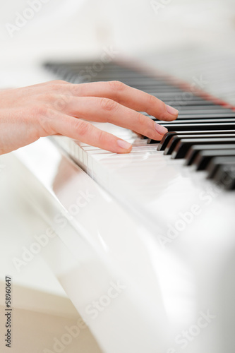 Close up of hand playing piano