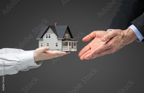 Close up of hands giving home model to other hands