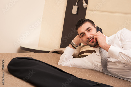 Young businessman talking at the phone in hotel room.