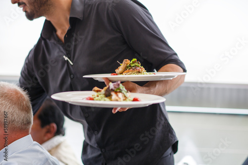 Waiter carrying a plate with salad dish on a wedding.