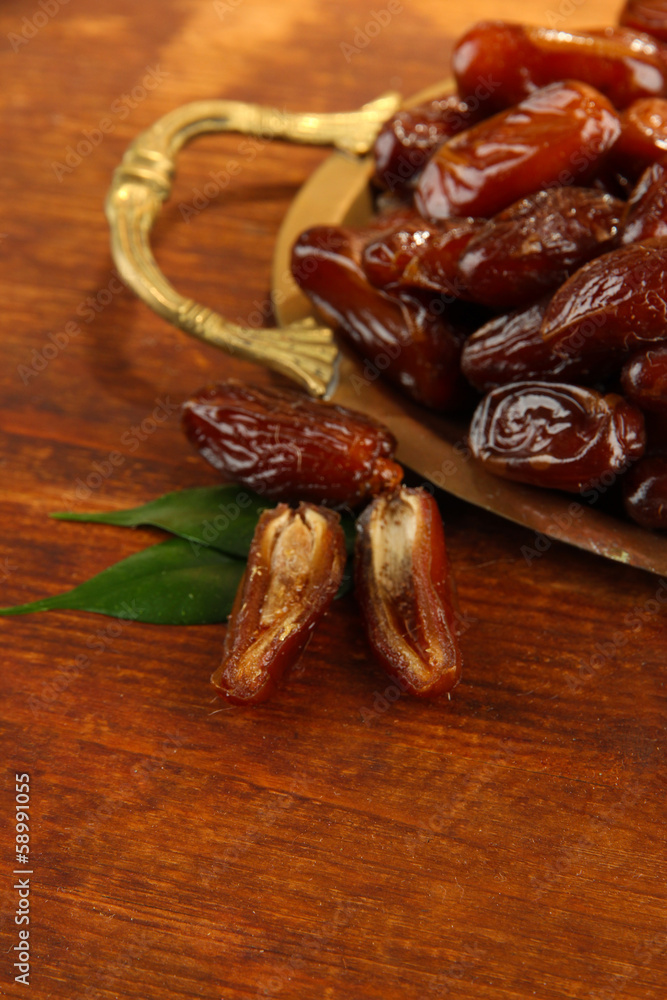 Dried dates on metal tray on wooden background Dried dates on metal tray on wooden background