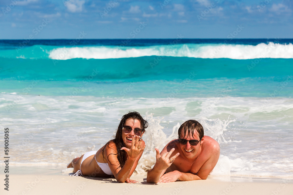 Fototapeta premium Young romantic couple laying on sandy beach