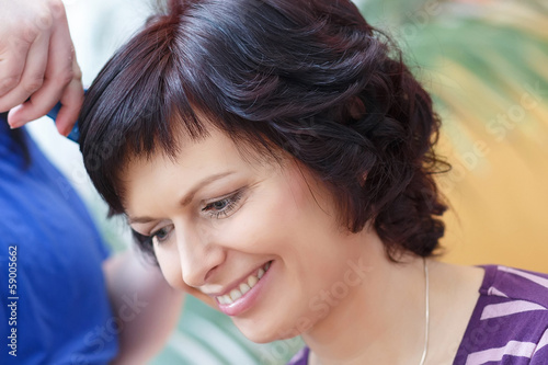 stylist prepares hairstyle for beautiful woman