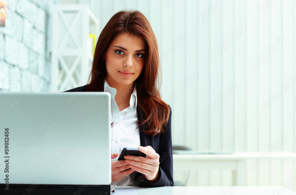 Young serious businesswoman holding smartphone Young serious businesswoman holding smartphone