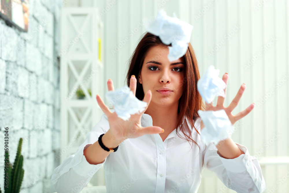 Young frustrated businesswoman throwing paper in camera Young frustrated businesswoman throwing paper in camera