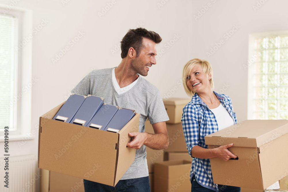 Happy couple carrying cardboard boxes in new apartment Happy couple carrying cardboard boxes in new apartment