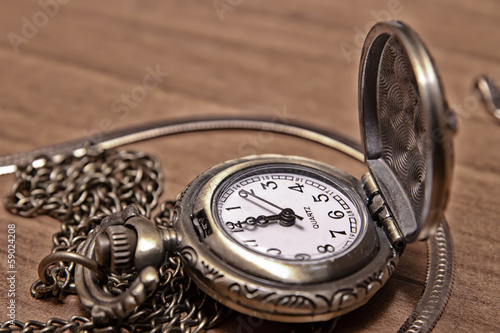 Pocket watch chain on the background of a wooden Desk