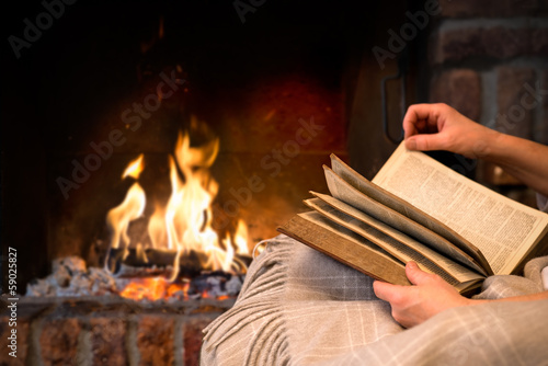 reading book by fireplace photo