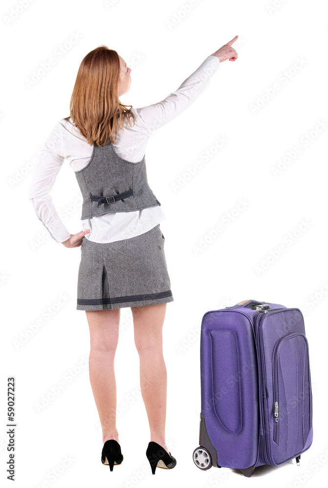 Beautiful young woman in dresstraveling with suitcas and pointin Beautiful young woman in dresstraveling with suitcas and pointin