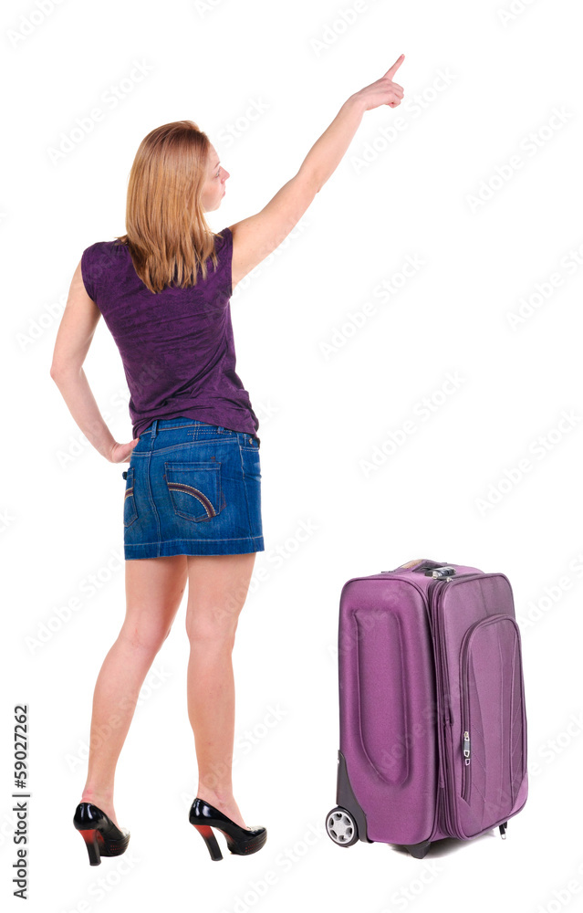 Beautiful young woman in dress traveling with suitcas and point Beautiful young woman in dress traveling with suitcas and point