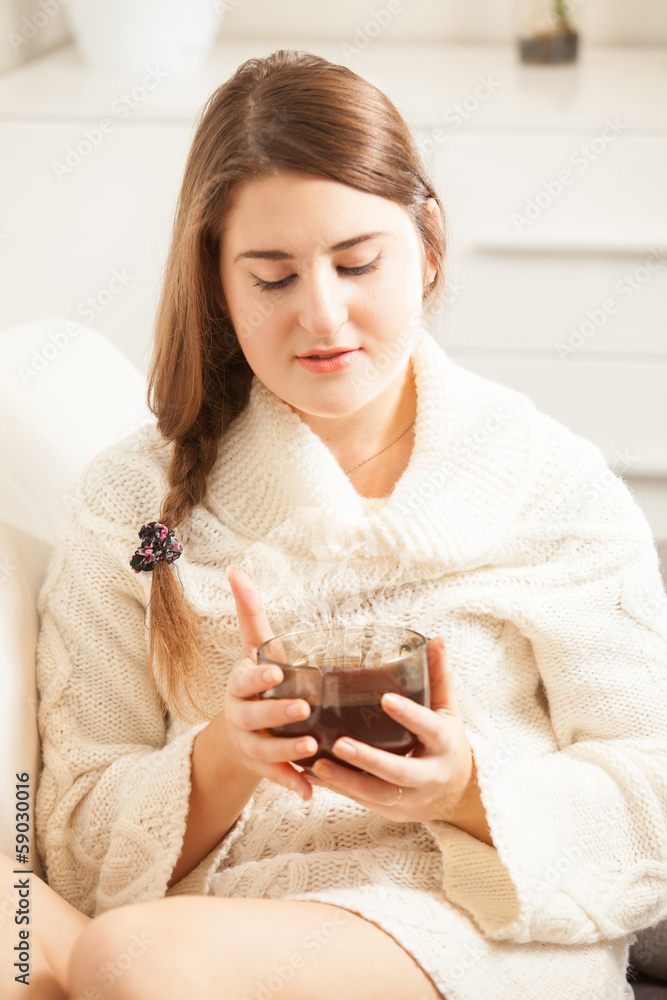 Beautiful brunette woman sitting on sofa on holding vaporing tea Beautiful brunette woman sitting on sofa on holding vaporing tea