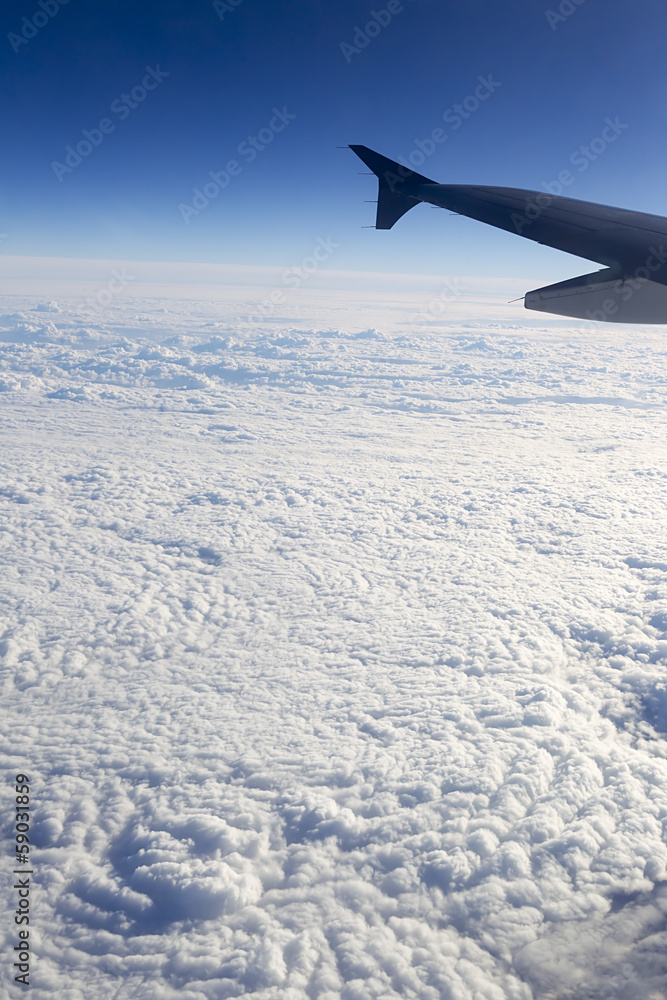 Fototapeta premium Wing of airplane flying above the clouds in the sky
