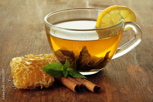 Transparent cup of green tea with honey and cinnamon