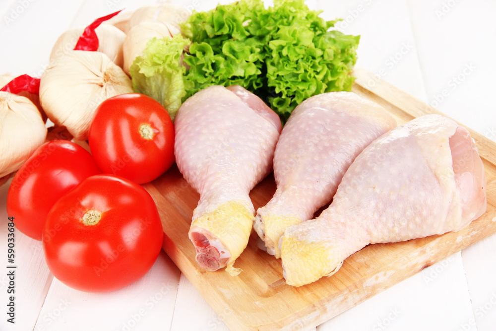 Raw chicken legs on wooden board close up Raw chicken legs on wooden board close up