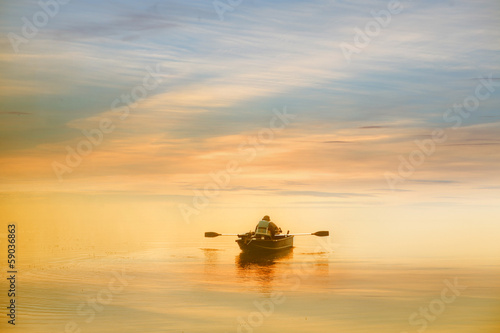 Obraz na plátně Lonely man boating in the dawn