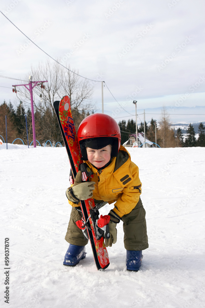 The boy in red helmet lift ski