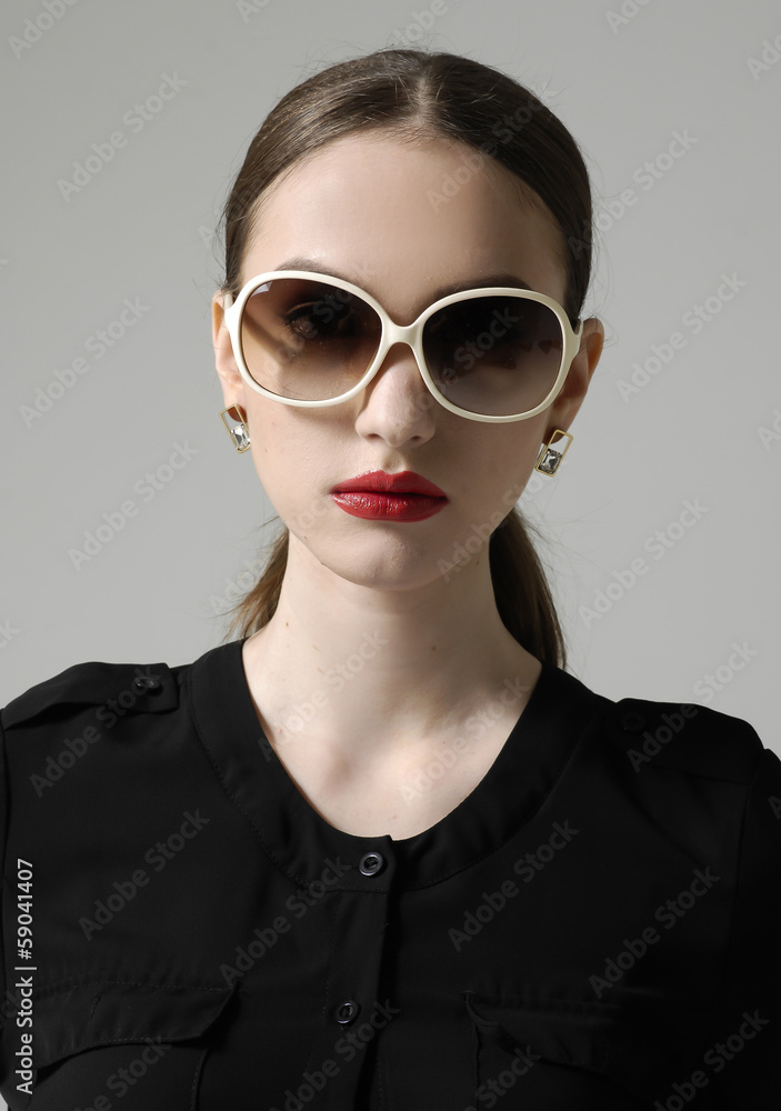 Fashion woman portrait wearing sunglasses on gray