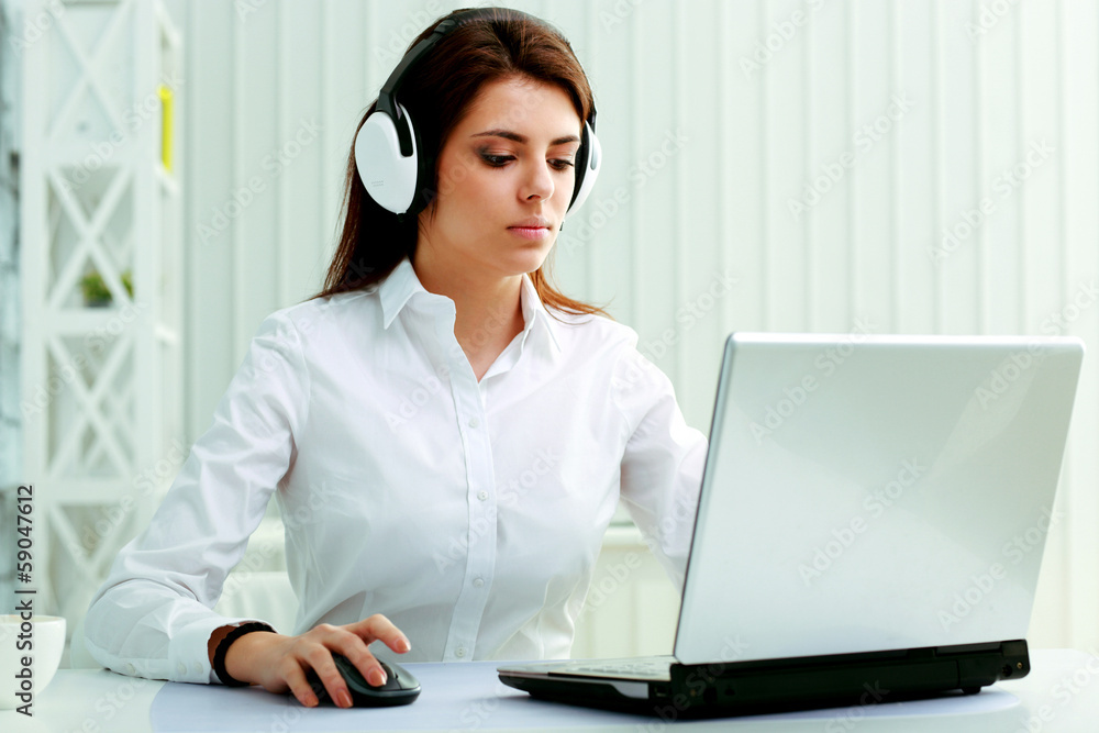 Young businesswoman in headphones working on a laptop at office Young businesswoman in headphones working on a laptop at office
