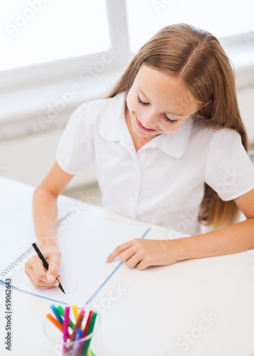 little student girl drawing at school