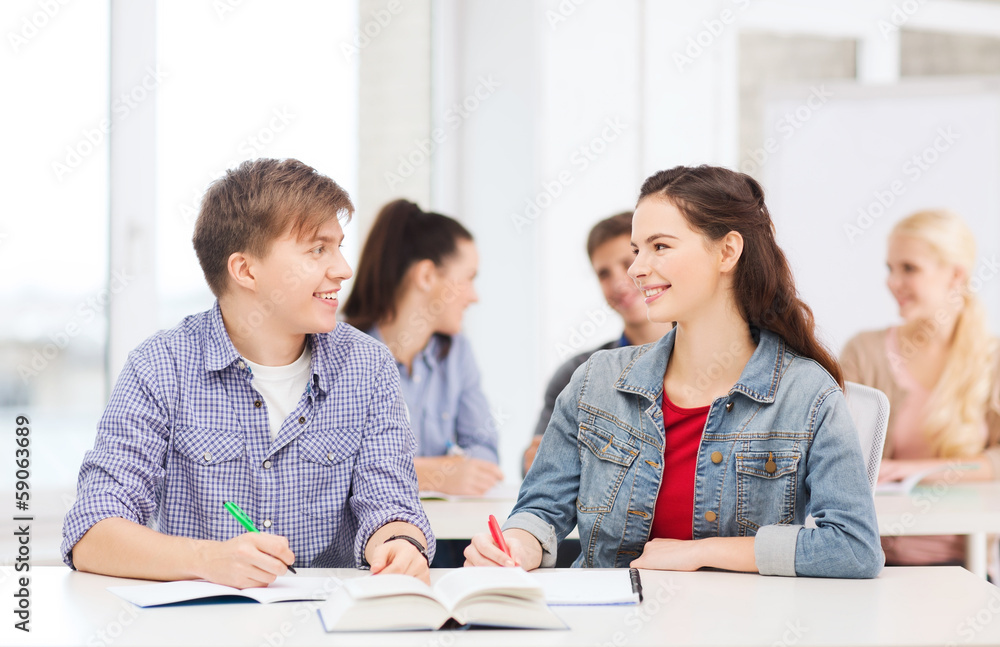 two teenagers with notebooks and book at school