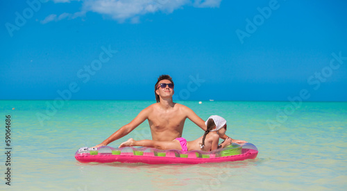 Little girl with young father on an air mattress in the sea
